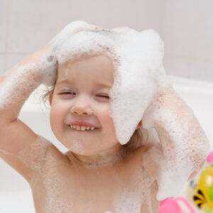 Baby girl washing her hair with shampoo